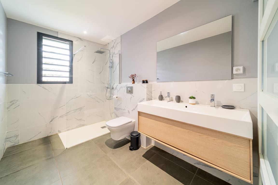 Salle d’eau avec douche à l’italienne, double vasque et grand miroir
