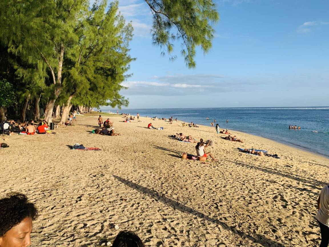 Plage de sable blond bordée de filaos avec le lagon turquoise en fin de journée