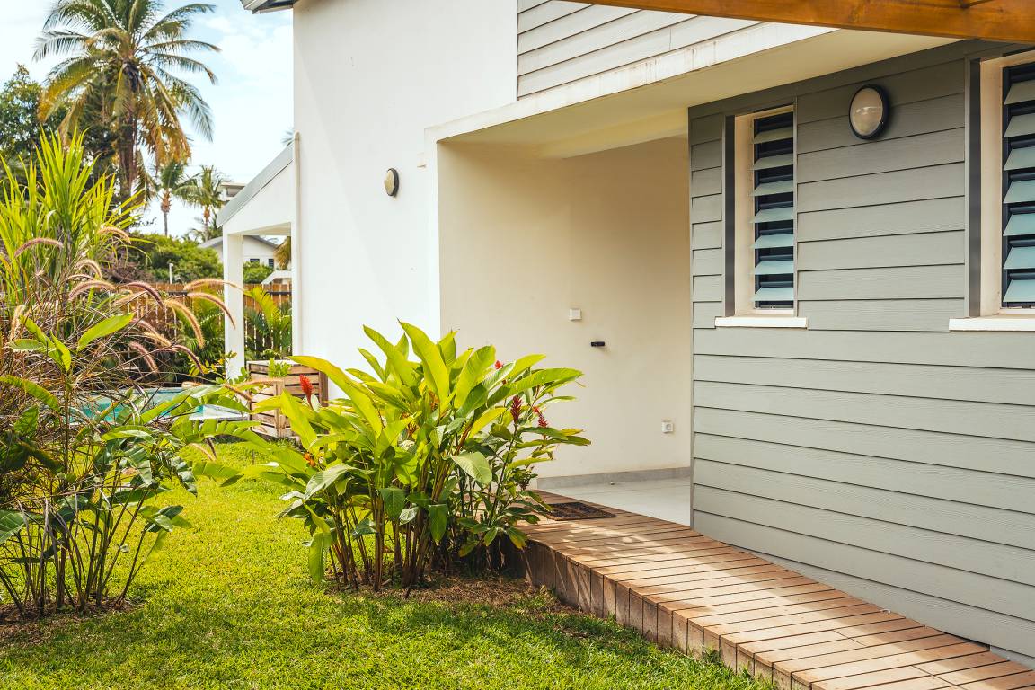 Chemin de bois dans le jardin tropical devant la façade de la villa